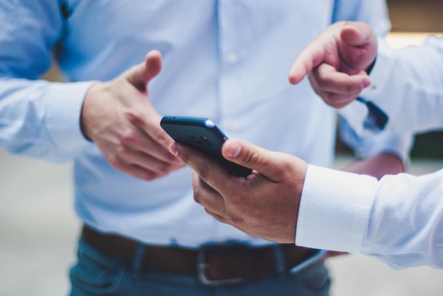 a man holding a mobile phone showing it to another person